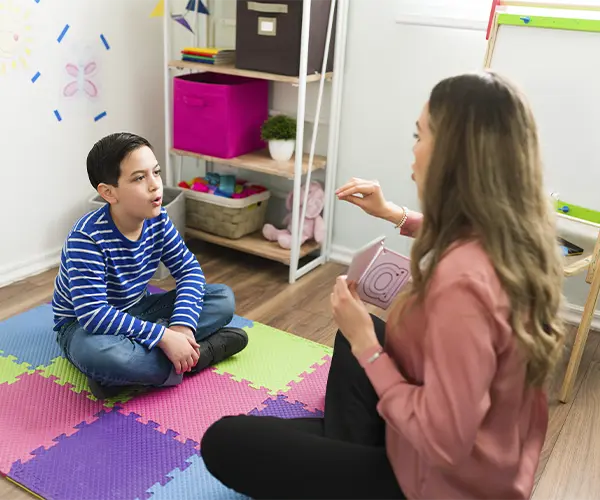 logopeda ense&ntilde;ando a un ni&ntilde;o a pronunciar