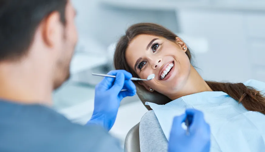 paciente sonriendo mientras el dentista de Sanitas le revisa la boca